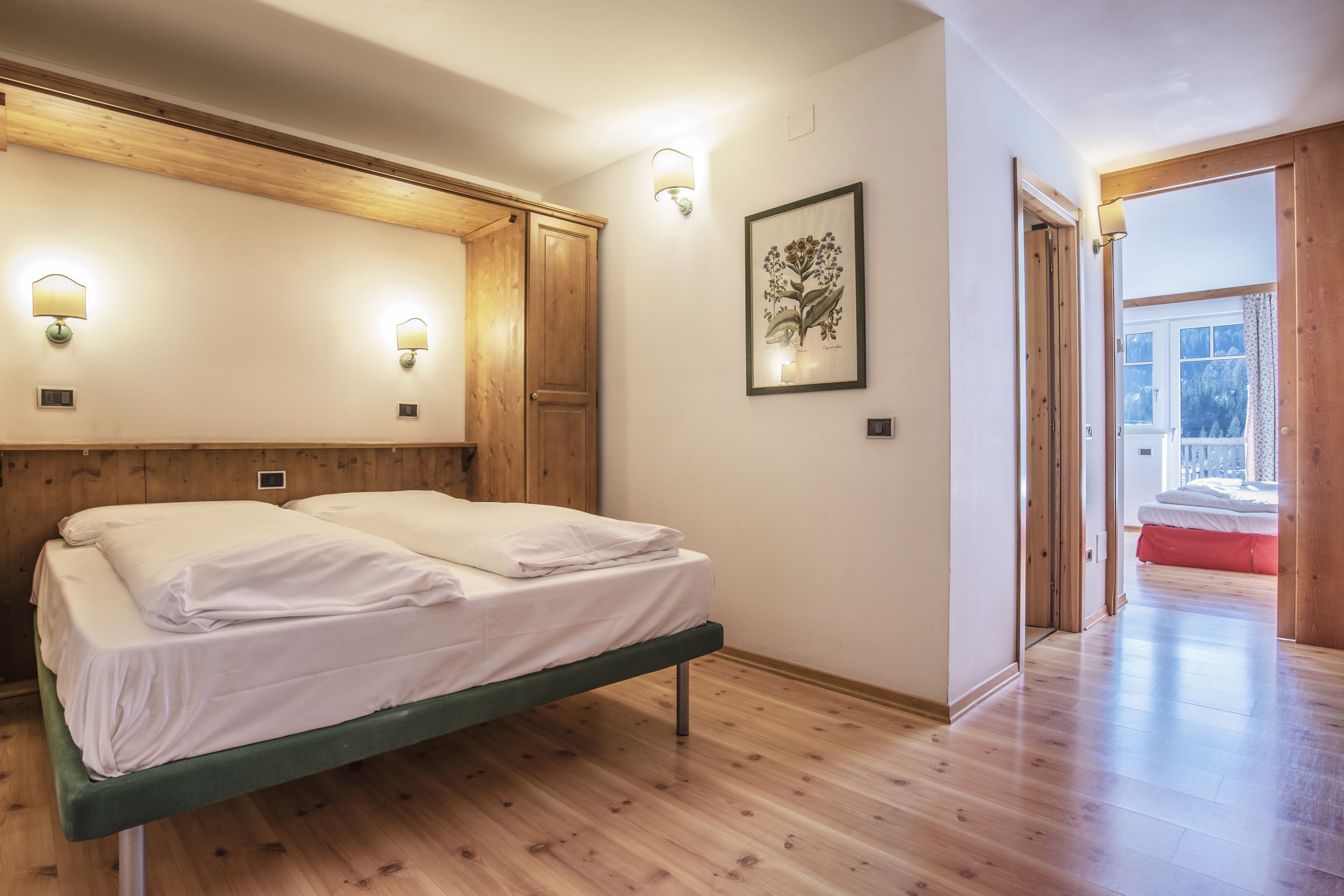 A room with a bed, wooden ceiling, wall-mounted lights, and a framed picture.