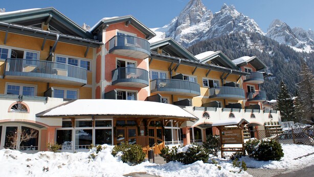 A multi-story hotel with balconies, a snow-covered entrance, and a mountain backdrop. - Sporting Clubresidence (Primiero San Martino di Castrozza)