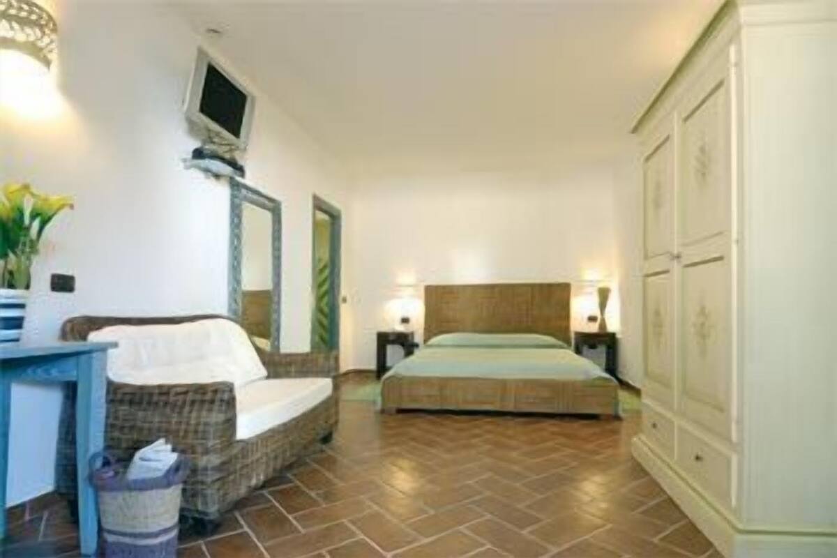 A bedroom with a bed, a desk, a chair, a TV, and a wardrobe.