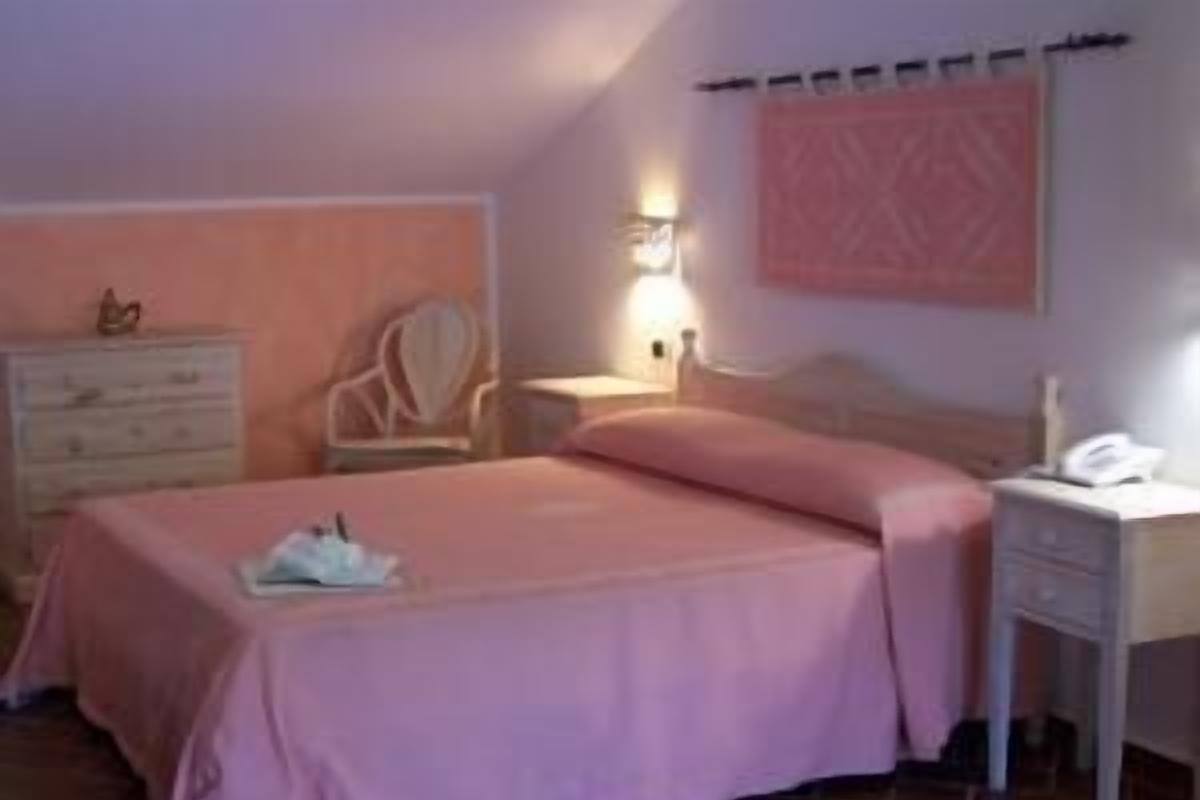 A bedroom with a bed, dresser, chair, bedside table, and lamp.