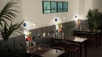 Un restaurant avec des tables et des chaises, des luminaires fixés au mur et des plantes en pot.