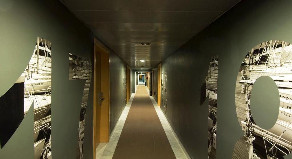 A hallway with a central carpeted walkway flanked by walls with mirrored panels reflecting construction images.