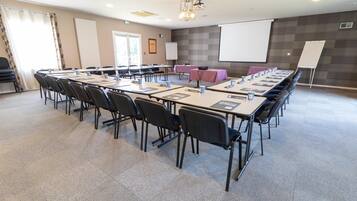 A conference room with a long table, chairs, a projector screen, and a whiteboard.