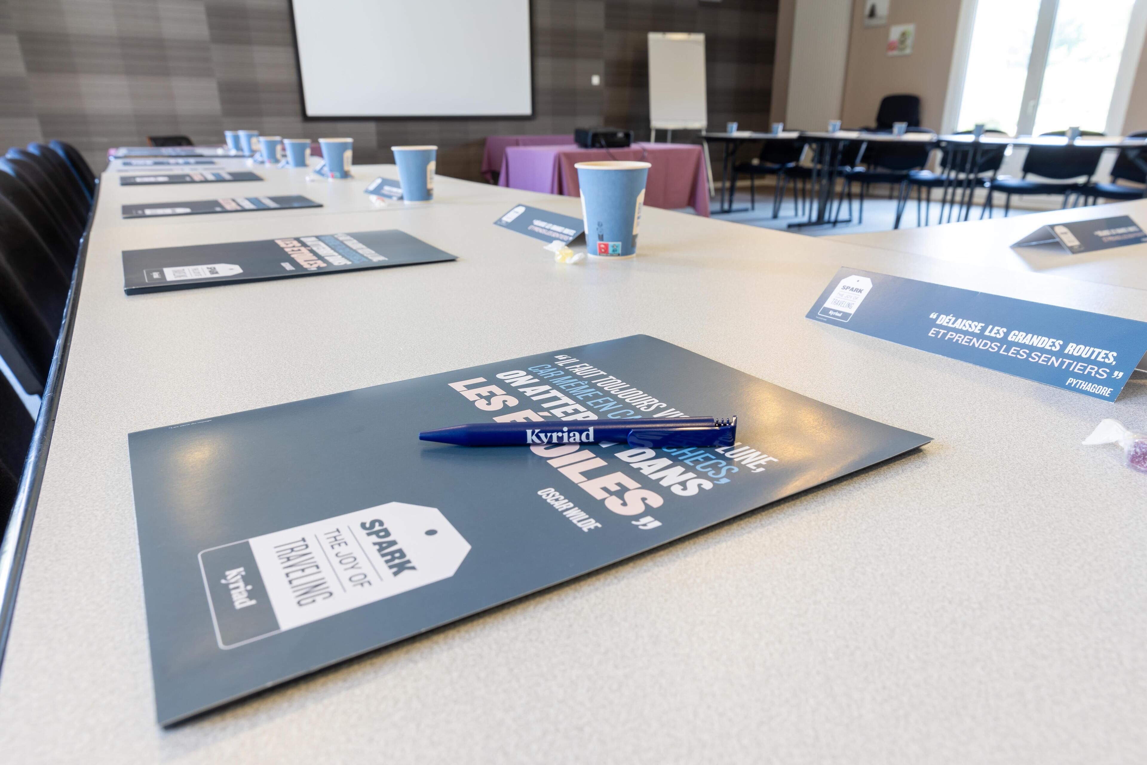 Une salle de conférence équipée de tables, de chaises et de badges nominatifs.
