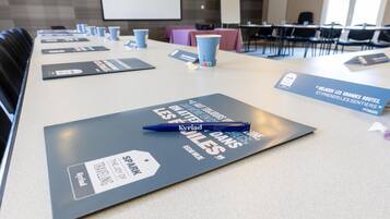 Une salle de conférence équipée de tables, de chaises et de badges nominatifs.