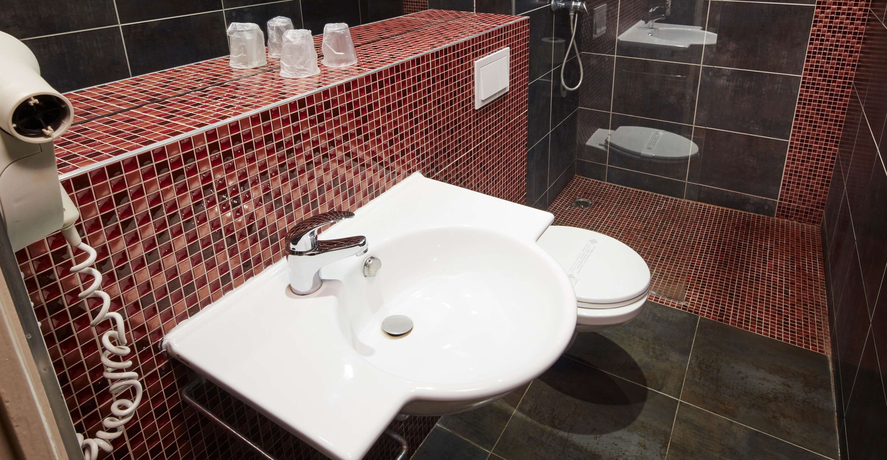 A bathroom with a white sink, a toilet, and a shower area.