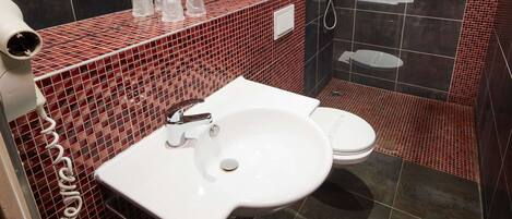 A bathroom with a white sink, a toilet, and a shower area.