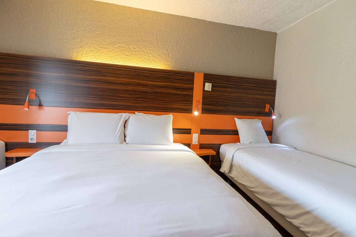 A hotel room with two beds, a wooden headboard, and a small table.