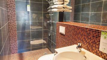 Une salle de bain moderne avec une douche à parois de verre, un lavabo blanc et un mur recouvert de carreaux.