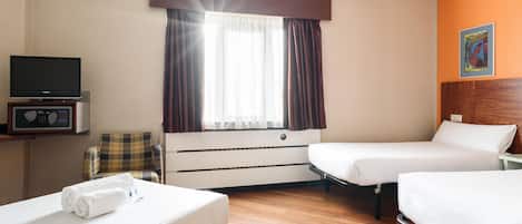 Habitación de hotel con dos camas, una televisión, una silla y una ventana con cortinas.