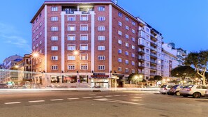 Un hotel de diverses plantes amb façana de maó vermell, múltiples balcons i un senyal que indica que és un hotel.