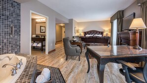 Una habitación de hotel con baño, comedor, zona de estar y cama.