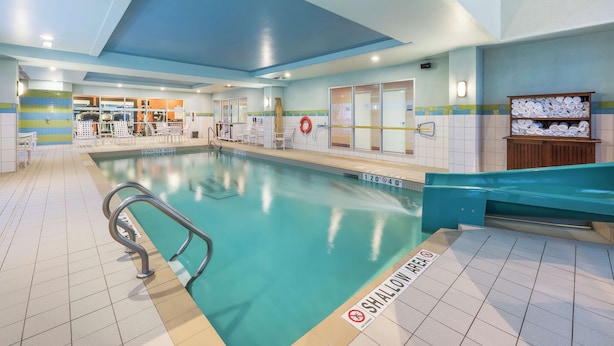 Una piscina interior con una zona poco profunda, paredes de azulejos y un banco a lo largo del borde.