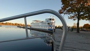 A river view with a boat docked at a wooden pier. - Kings Inn - Orillia (Orillia)