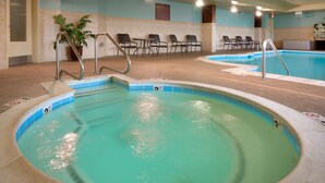 An indoor swimming pool with clear water, a lifeguard station, and several chairs and tables around the pool area. - Hilton Garden Inn Clarksville (Clarksville)