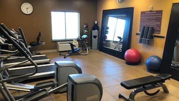 Un centre de remise en forme équipé de tapis de course, d’un vélo elliptique, d’un vélo d’appartement et de ballons d’exercice.