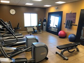 A fitness center with treadmills, an elliptical, a stationary bike, and exercise balls.