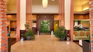 A spacious lobby with a high ceiling, multiple hanging pendant lights, and a central plant arrangement. - Hilton Garden Inn Clarksville (Clarksville)