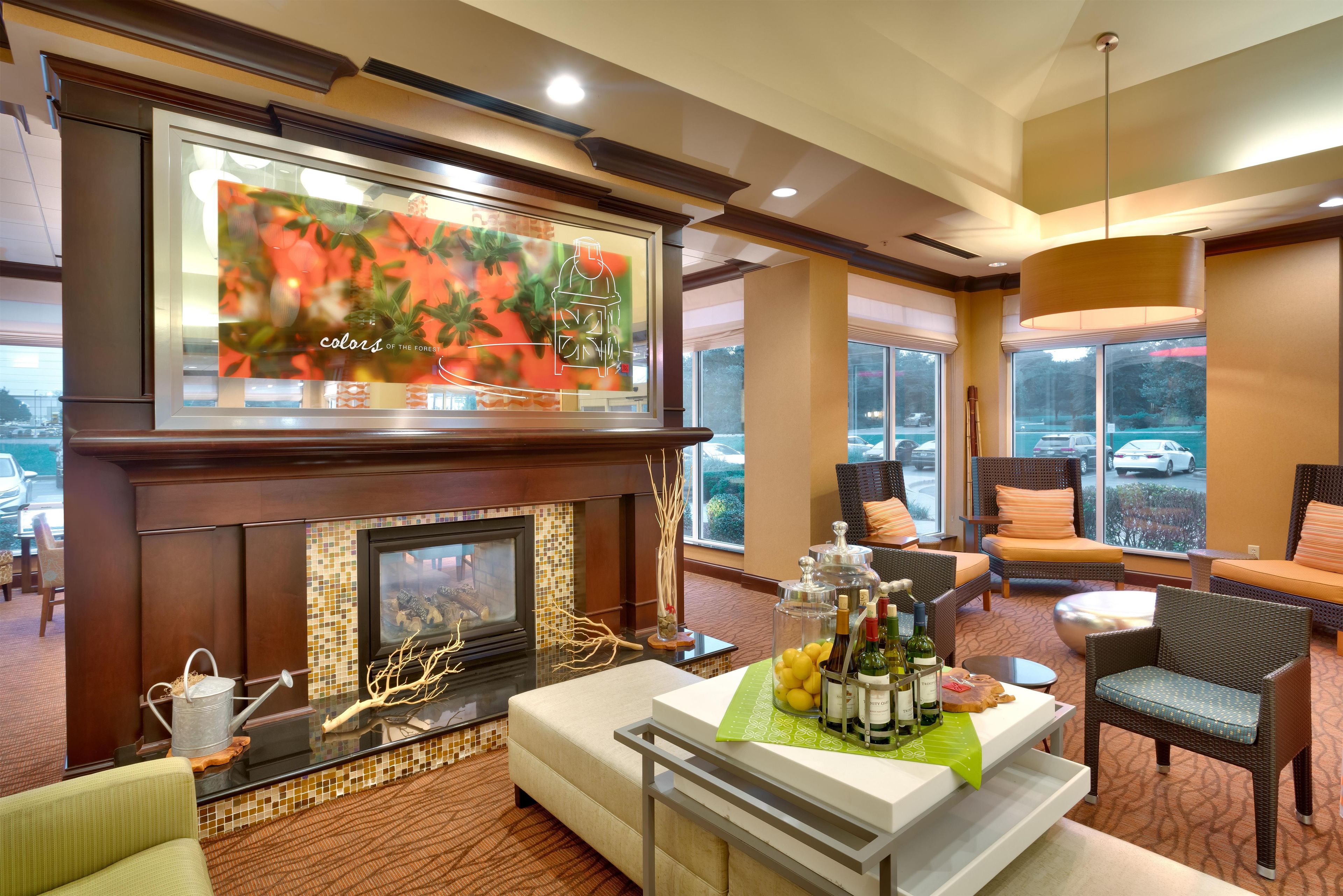 A hotel lobby with a fireplace, seating area, and a large window offering a view of the parking lot.