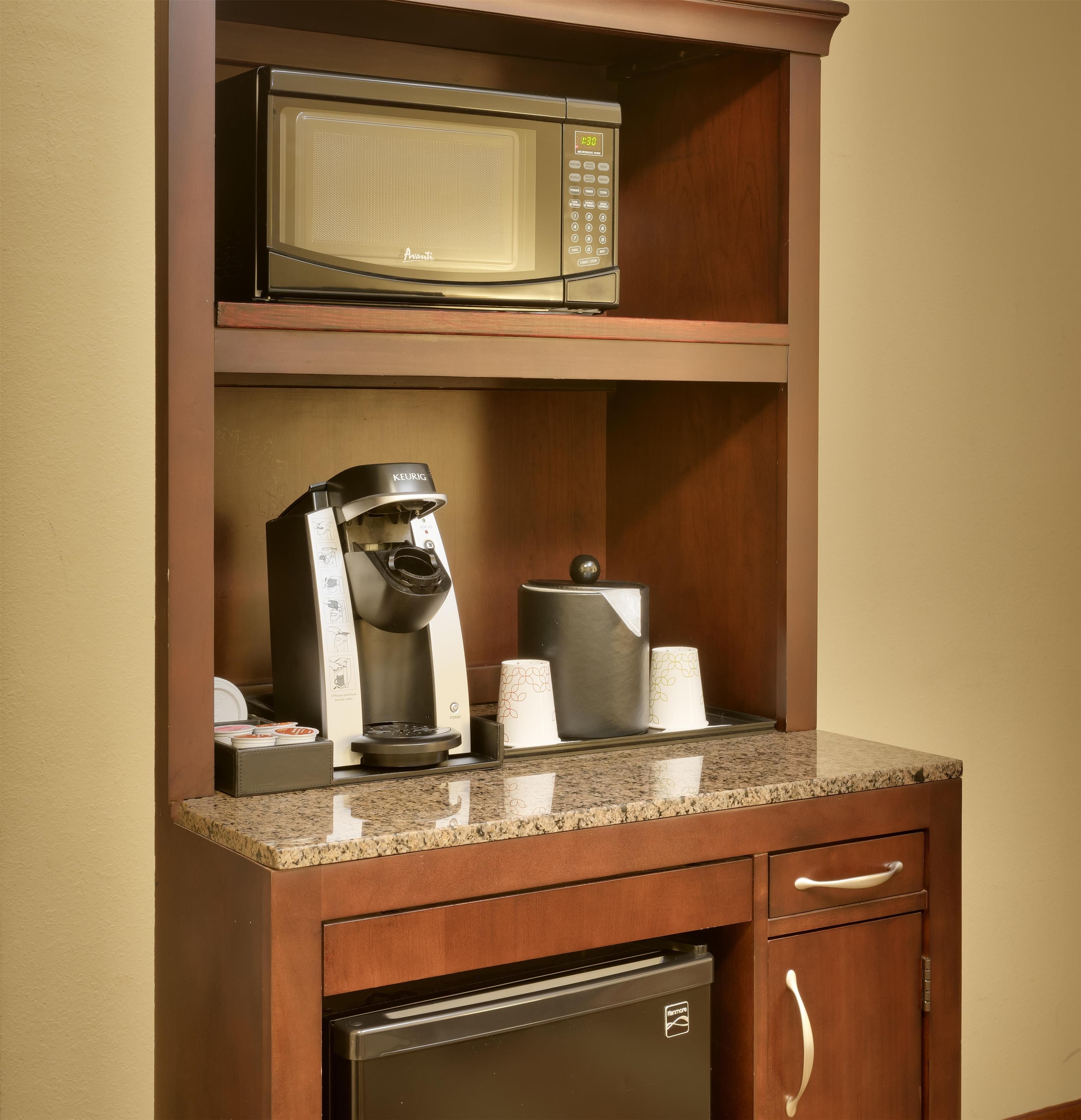 A kitchenette with a microwave, coffee maker, and paper towels.