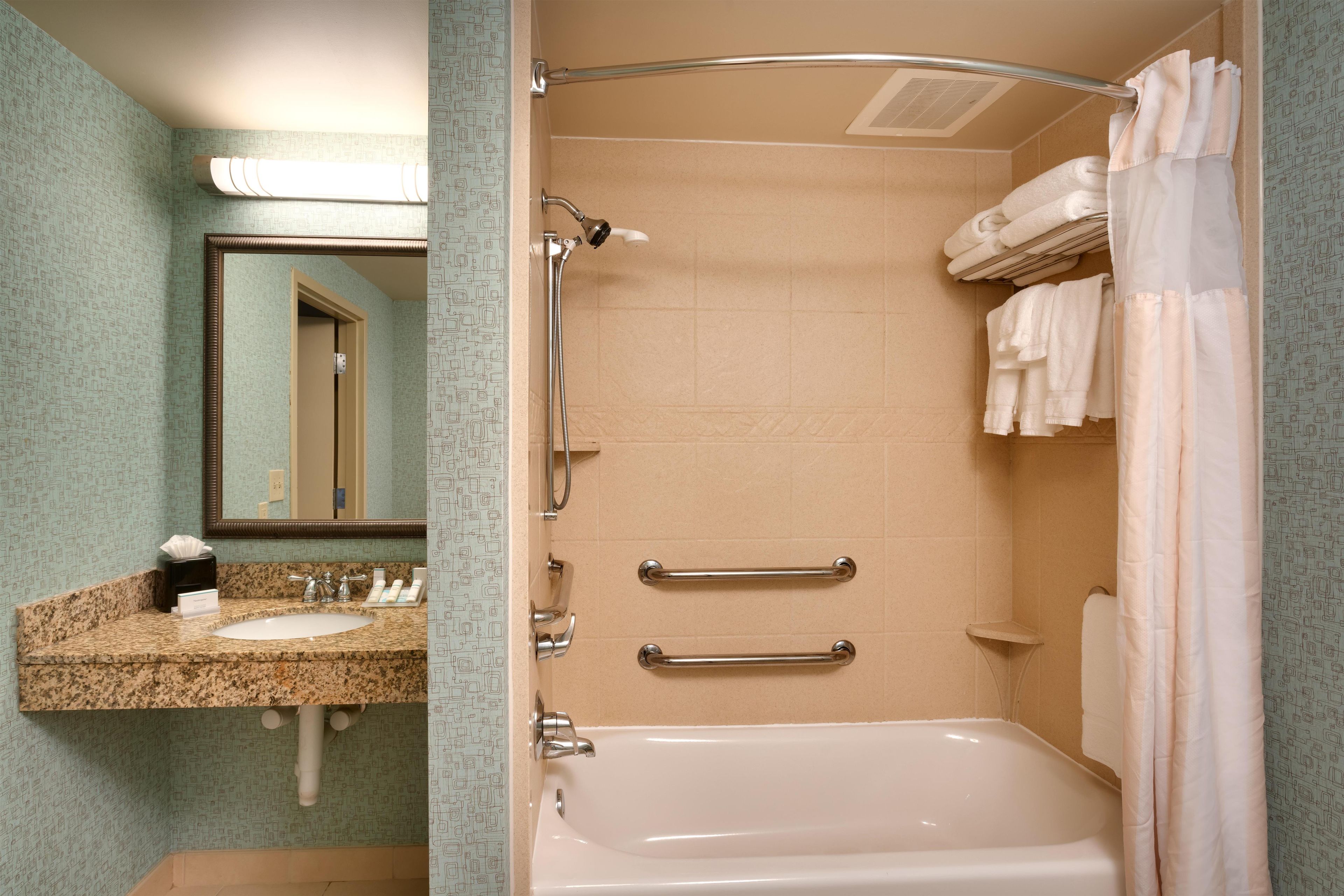 A bathroom with a sink, mirror, towel rack, and bathtub.