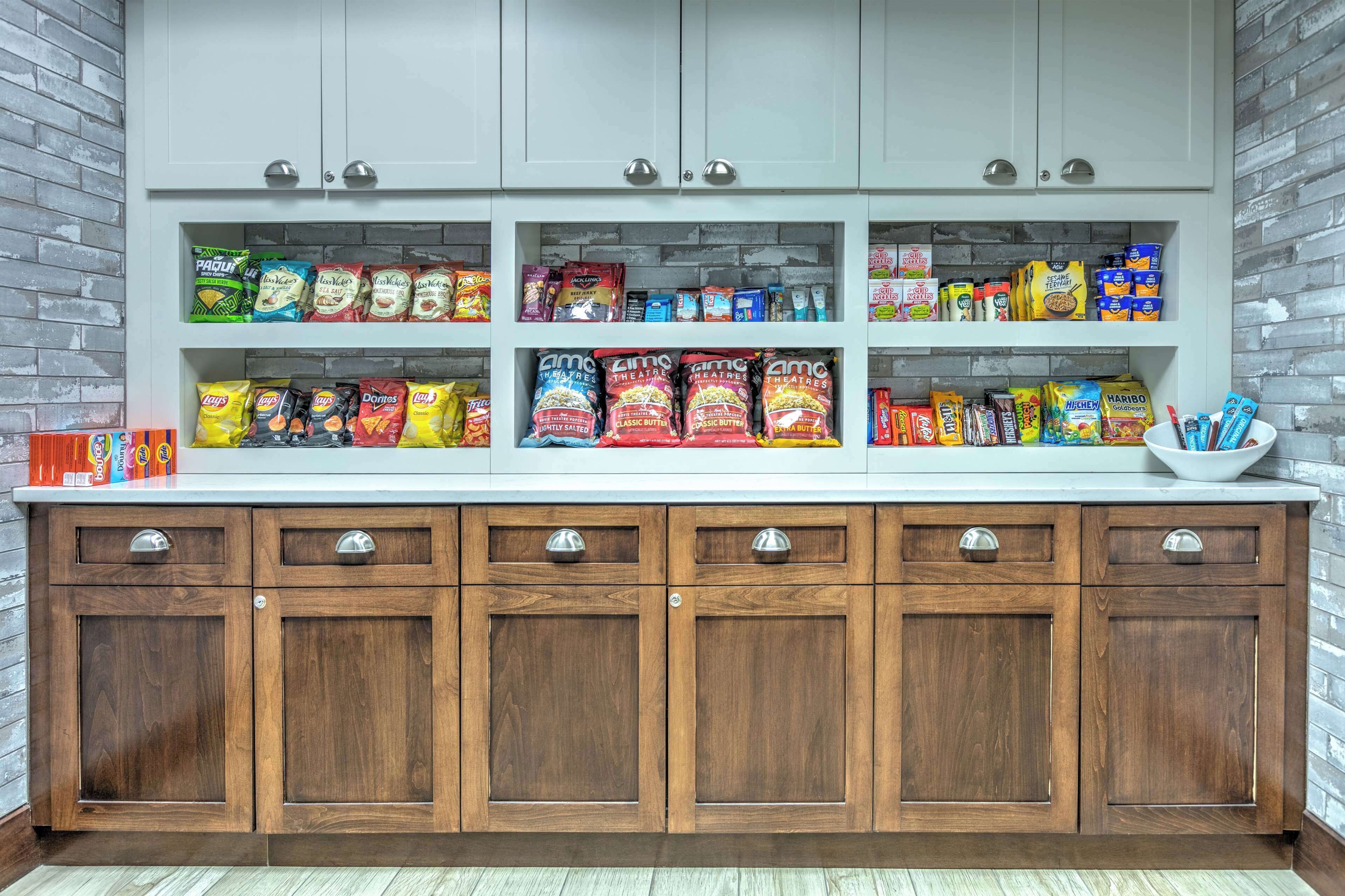 Een keuken met houten kasten en planken vol met diverse snacks en etenswaren.