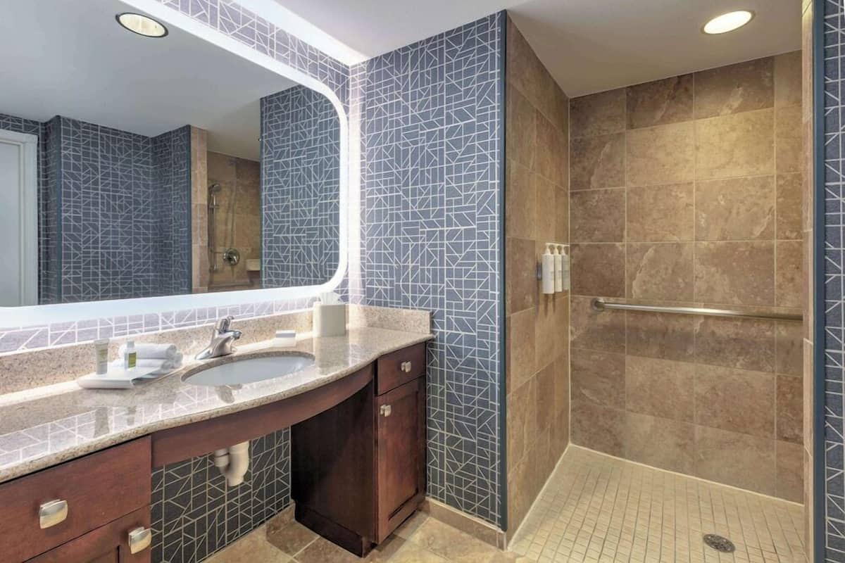 Une salle de bain moderne avec un grand miroir, un lavabo et un espace douche.