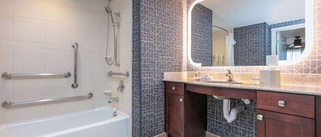 Une salle de bain comprenant une baignoire, une douche, un meuble-lavabo avec un miroir et un évier.