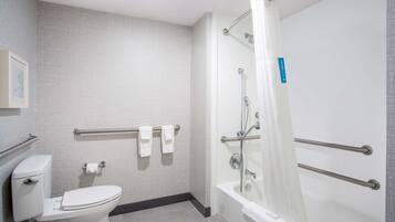 Un baño con inodoro, ducha con puerta de cristal y barandilla.