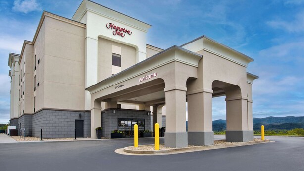 A Hampton Inn hotel with a modern facade, a welcoming entrance, and a view of the surrounding landscape.