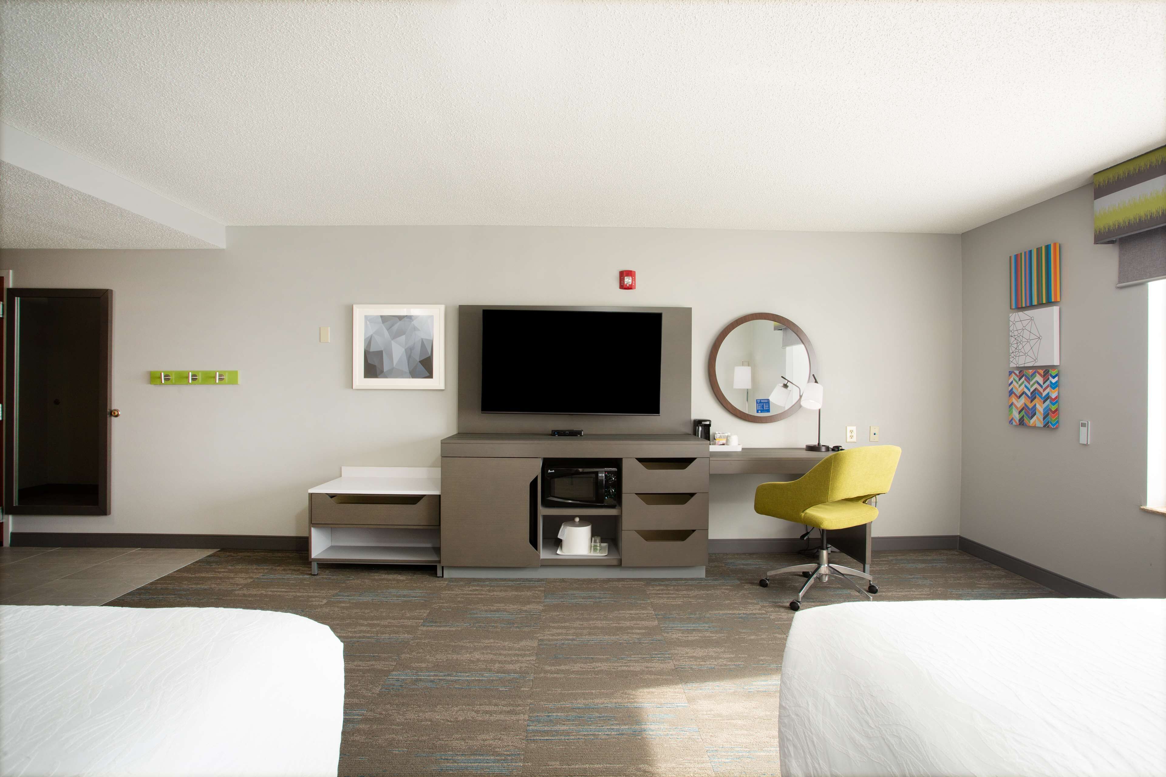 A hotel room with a bed, a desk with a flat-screen TV, a chair, and a microwave.