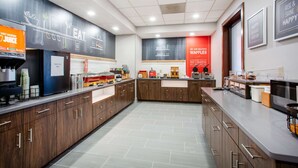 A modern kitchen with a breakfast bar, a juice dispenser, and a waffle station.