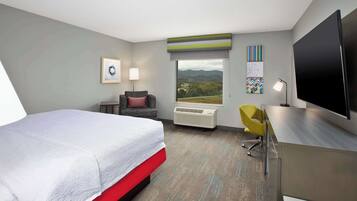 A hotel room with a bed, a desk, a chair, a TV, and a window with a view.