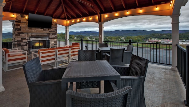 An outdoor patio with a stone fireplace, wicker furniture, and a view of the mountains. - Hampton Inn Elkins (Elkins)