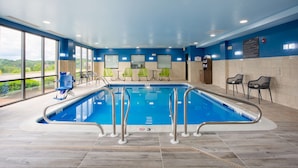 An indoor swimming pool with clear glass walls, a blue ceiling, and a view of greenery outside. - Hampton Inn Elkins (Elkins)
