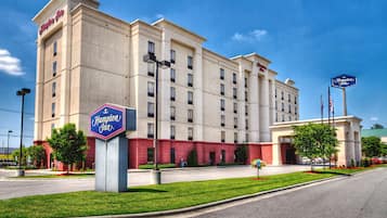 A Hampton Inn hotel with a beige facade, multiple windows, and a red lower section.