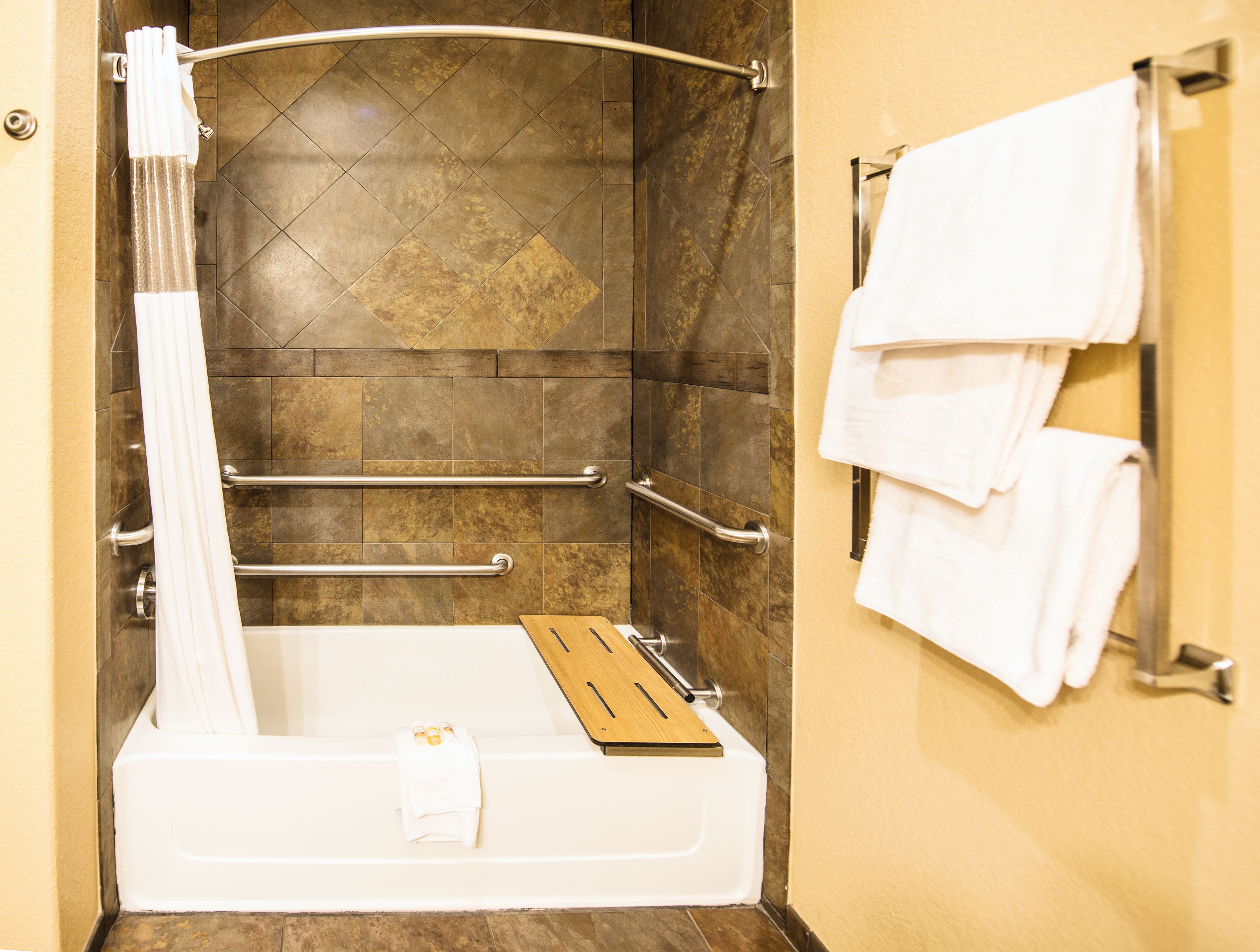 A modern bathroom with a bathtub, a shower area, and a towel rack.