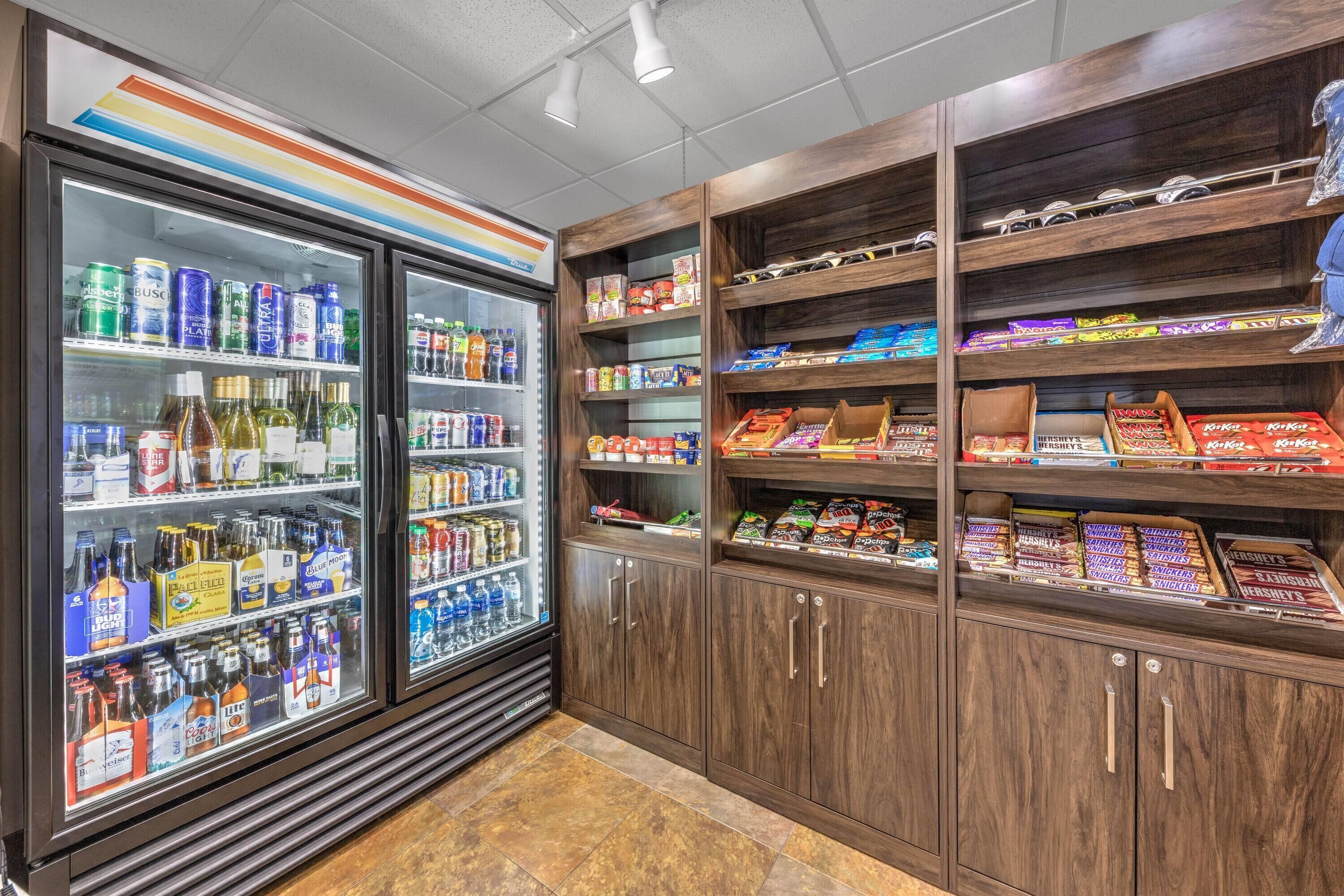 A refrigerated beverage display and shelves stocked with snacks and candy.
