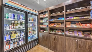 Un présentoir réfrigéré pour les boissons et des étagères remplies d’en-cas et de bonbons.