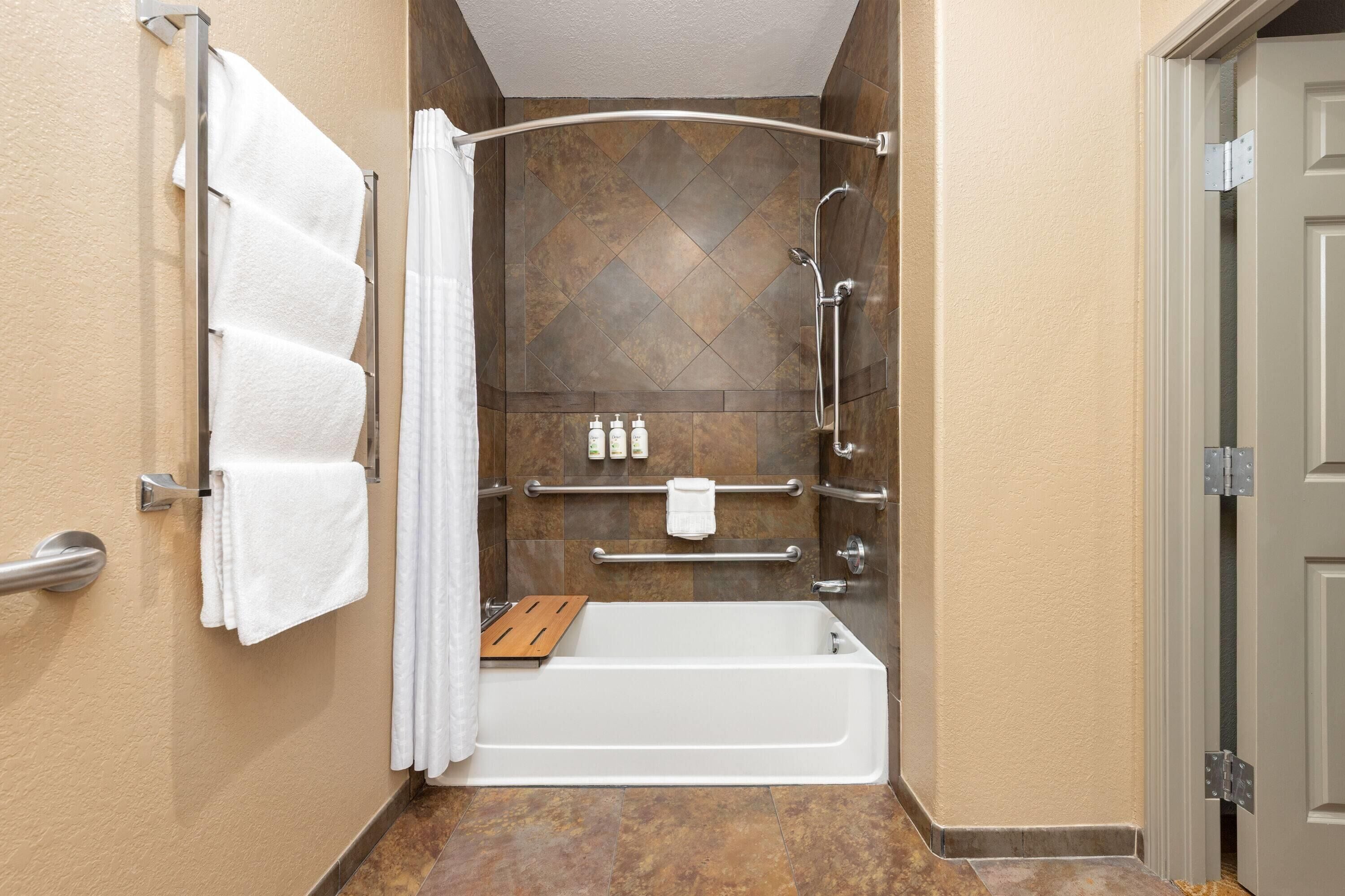 Une salle de bain moderne équipée d’une baignoire, d’une douche et de barres d’appui.