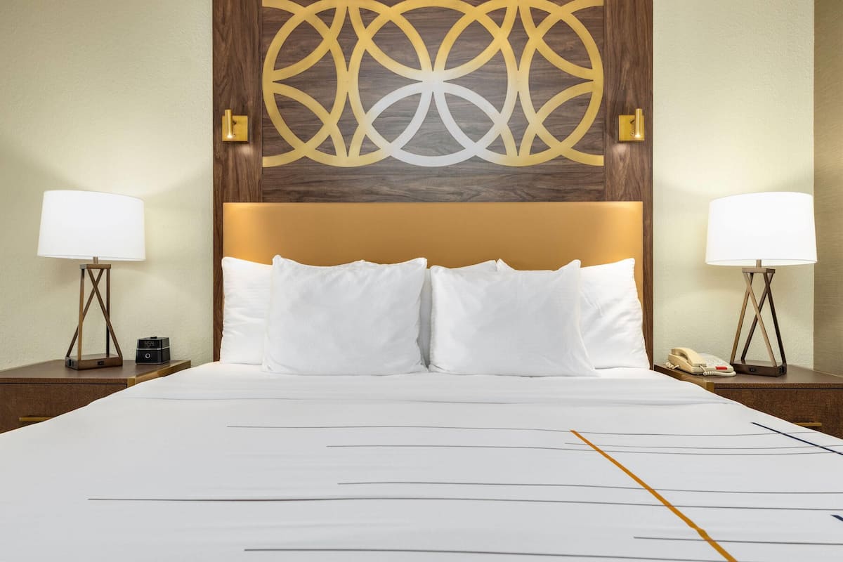 Hotelkamer met een groot bed, twee nachtkastjes met lampen, een decoratief paneel aan de muur, en een telefoon op één van de nachtkastjes.