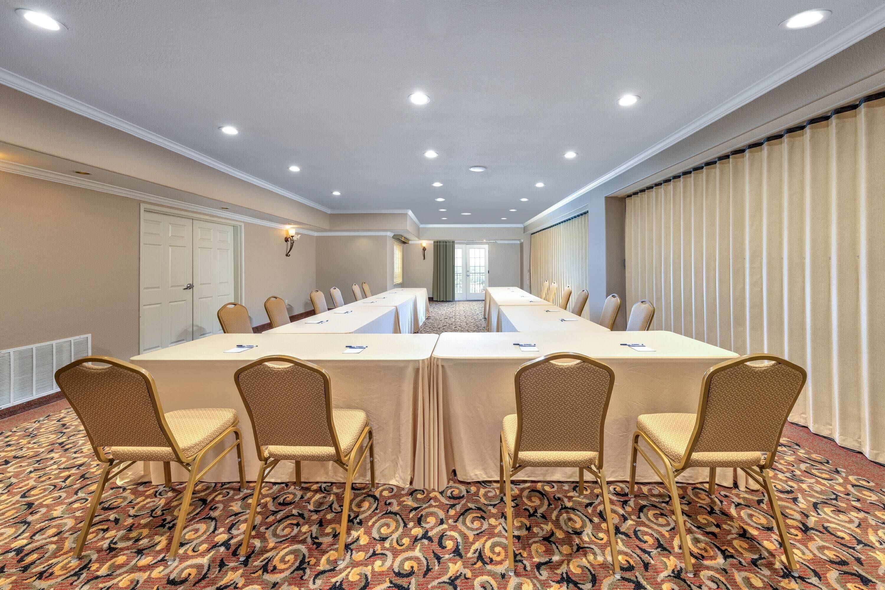 A conference room with a long table, four chairs, and a patterned carpet.