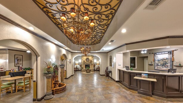 A spacious lobby with a central fireplace, a reception desk, and a chandelier.