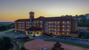 A large hotel with multiple balconies, a central tower, and a well-lit entrance.