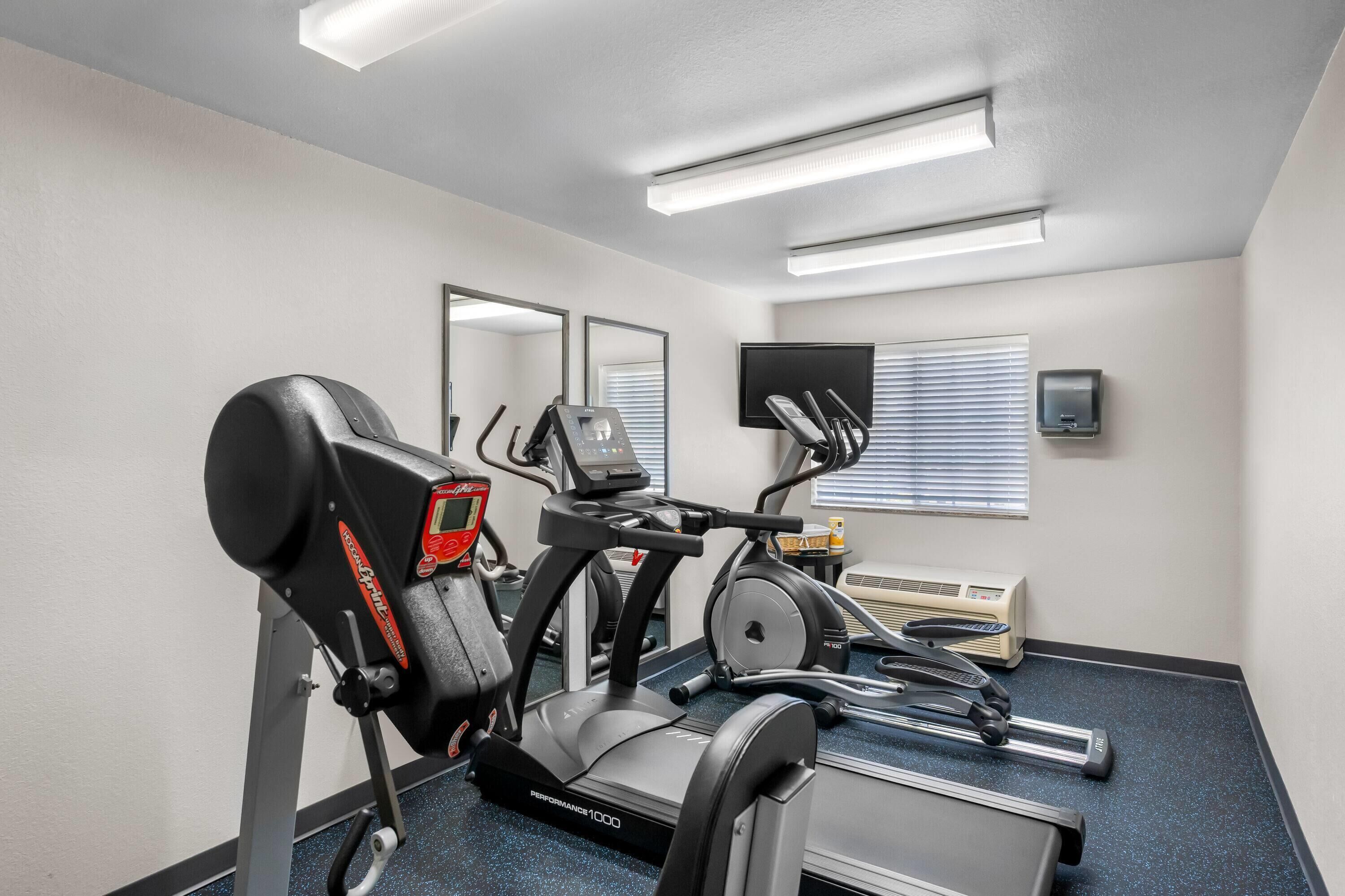 Un gimnasio con cinta de correr, elíptica y bicicleta estática.