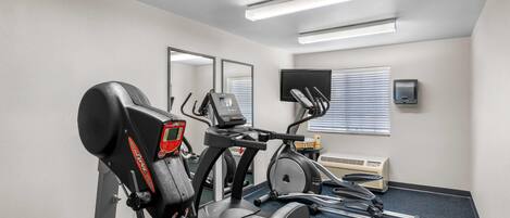 Un gimnasio con cinta de correr, elíptica y bicicleta estática.