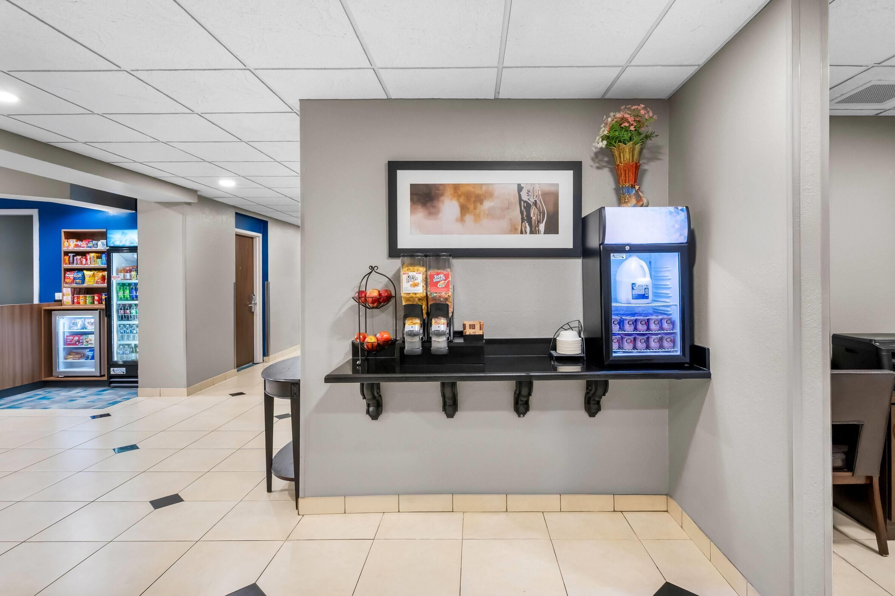 A reception area with a counter, vending machines, a refrigerator, and a framed picture on the wall.