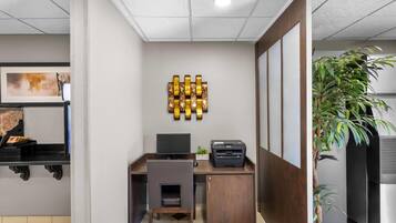 Een moderne kantoorruimte met een bureau, stoel, printer en decoratieve wandkunst.