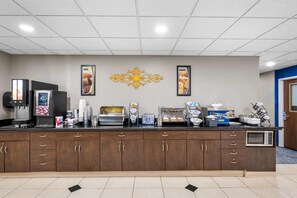 A hotel reception area with a counter, coffee machines, a microwave, and framed pictures on the wall. - Microtel Inn & Suites by Wyndham Conway (Conway)