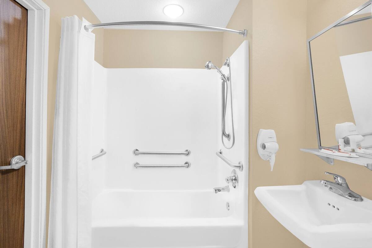 Ein Badezimmer mit Dusche, Waschbecken, Spiegel und Handtuchhalter.